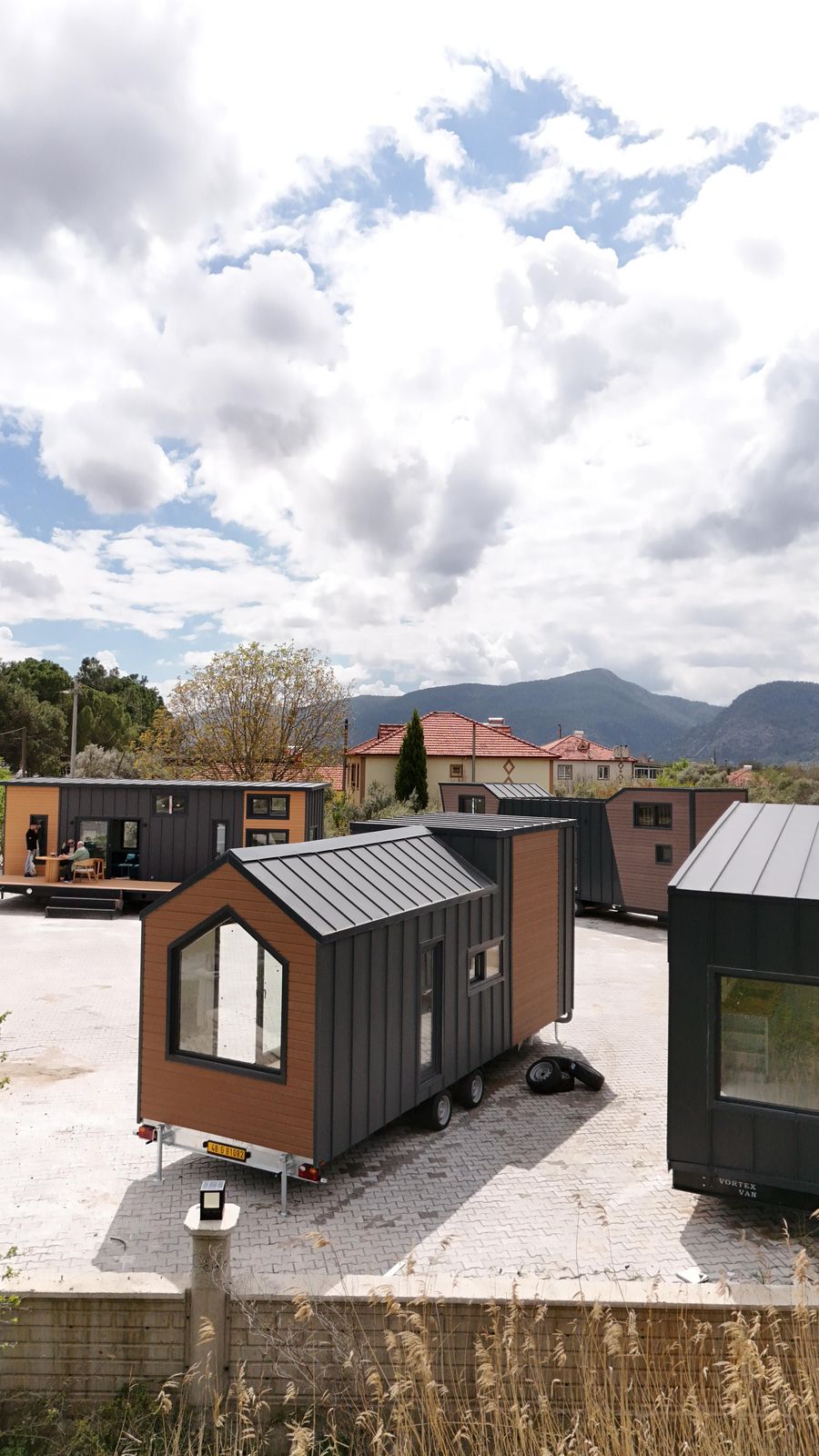 Two Tinyhouse Atelier lodges on plot, foothills behind